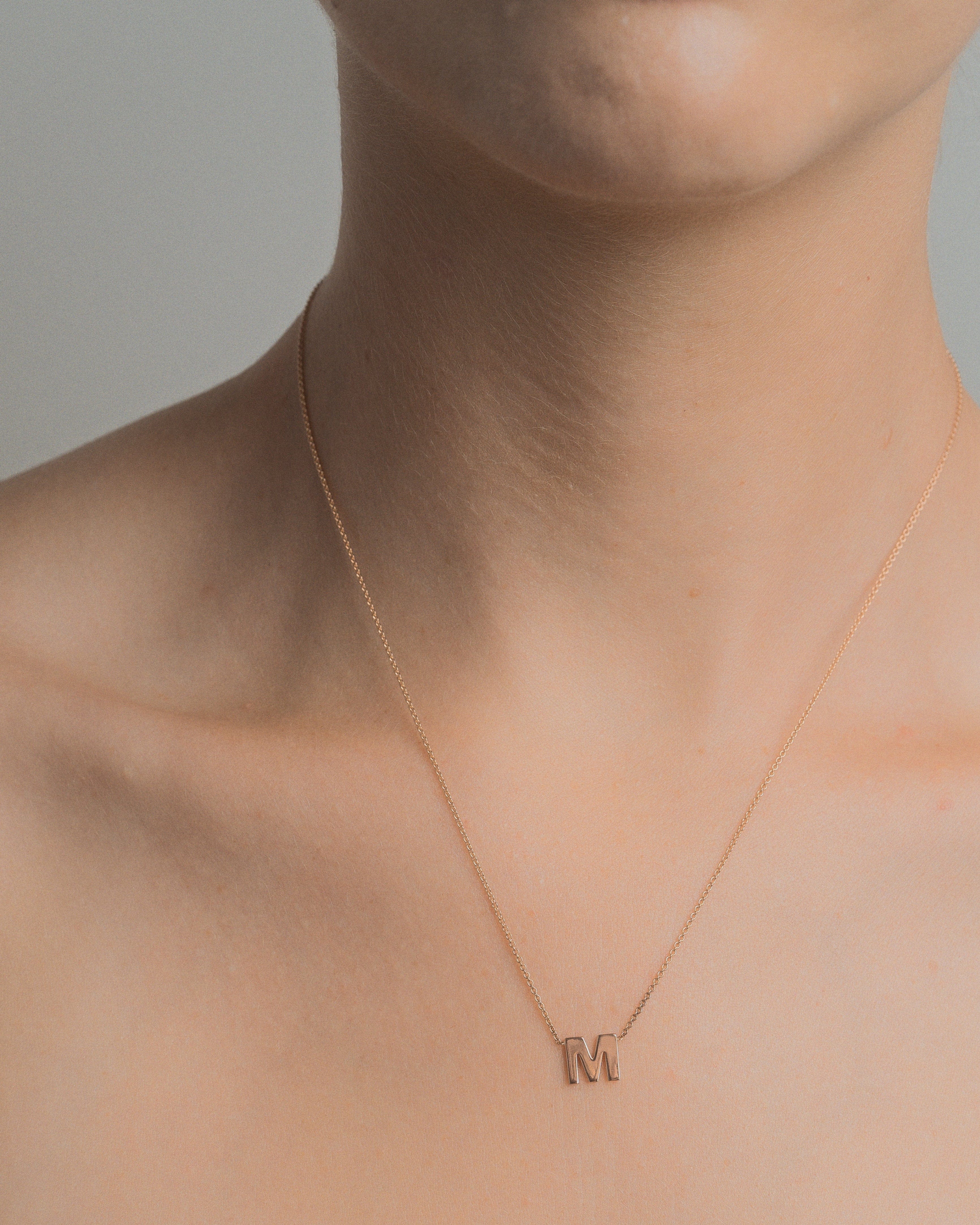 Model wearing petite rose gold initial necklace.