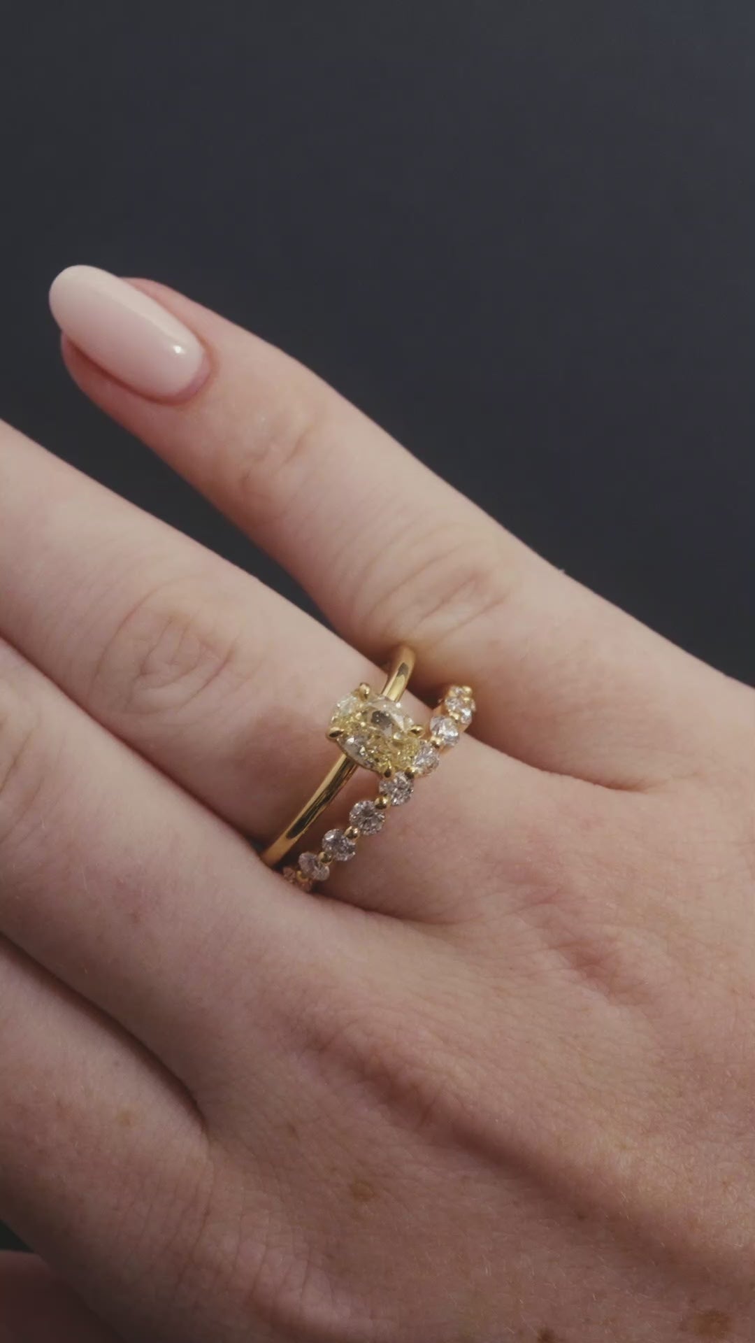 Close up of model's hand wearing a solitaire oval cut yellow diamond engagement ring with single claw set diamond ring.